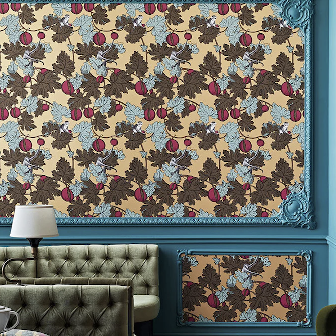 Fornasetti-behang in een woonkamer met groene bladeren, rode vruchten en tekeningen van apen tussen het gebladerte.