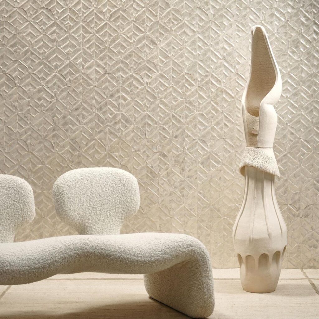 Organisch gevormde witte designbank en sculptuur voor een wand met glanzend patroonbehang ARTE Luster Abalone 70321.