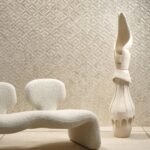 Organisch gevormde witte designbank en sculptuur voor een wand met glanzend patroonbehang ARTE Luster Abalone 70321.