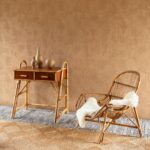 Sfeervolle interieurhoek met de ARte-Tali Tamba 60727 behang, een rotan stoel met schapenvacht en een bamboe bijzettafel met decoratieve vazen.