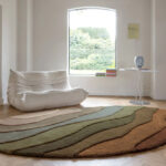 Rond vloerkleed Allegro-High-AEOH35894 met golvend patroon in aardetinten in een minimalistisch ingerichte woonkamer.