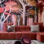 Rode loungebank in een moderne woonkamer met een kleurrijk Arte Alaya Banyan Red Blossom panorama-behang van abstracte bomen.