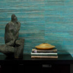 Zwarte kast met sculptuur, boeken en gouden schaal, tegen turquoise Arte All Naturals Camago 14003A behang.