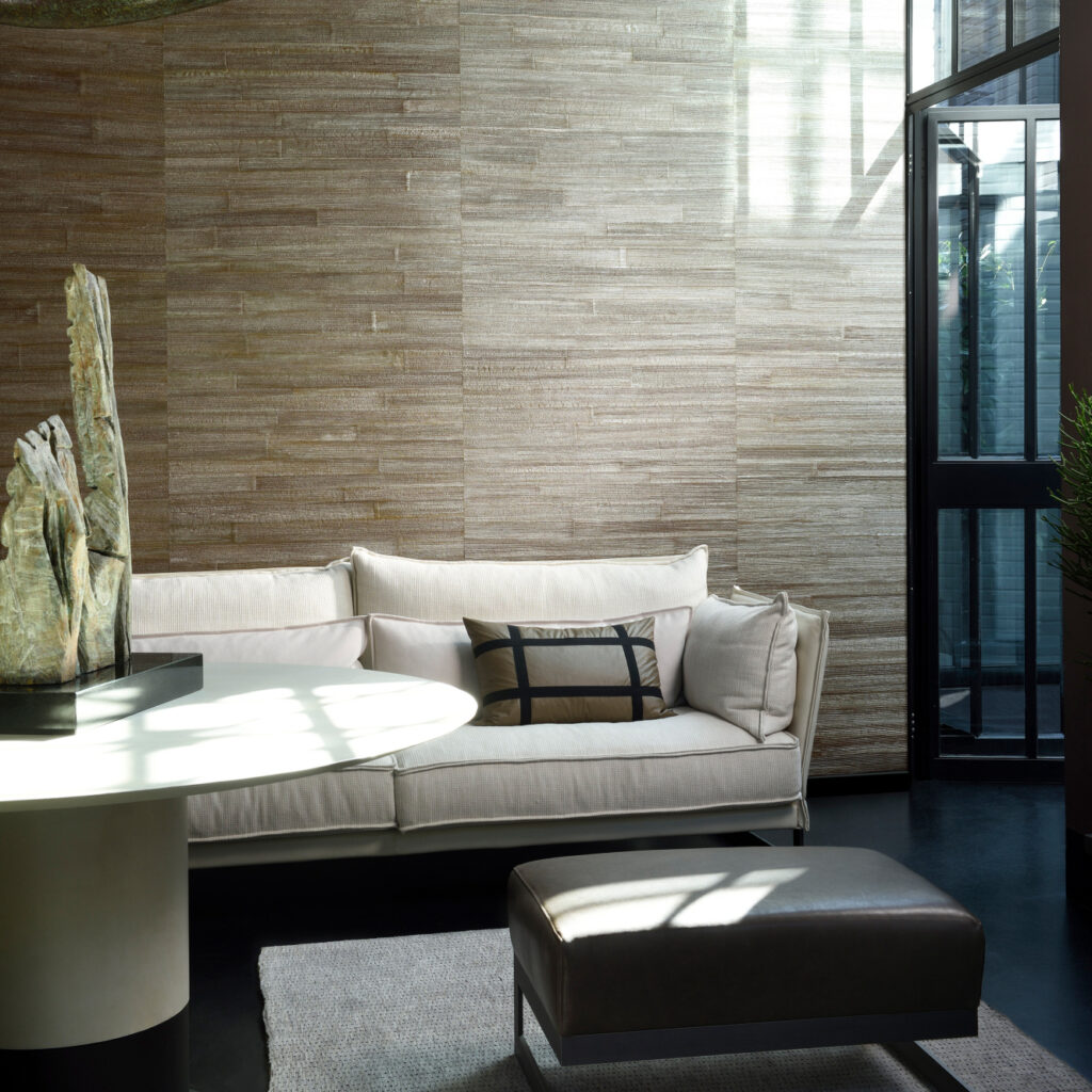 Moderne woonkamer met Arte All Naturals Camago 14009A wandbekleding, een lichtbeige bank en elegante decoratie.
