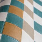 Close-up van een Arte Atelier Plaza wandbekleding met een golvend patroon van vierkante vlakken in groenblauw, okergeel, beige en wit.