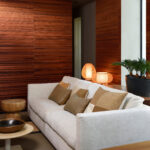 Woonkamer met Arte Casalian 14023 behang, een lichtkleurige bank, warme houten accenten en sfeerverlichting.