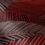 Close-up van het Arte Chintz behang uit de Essentials Les Tricots collectie met een abstract patroon in rood- en bruintinten.