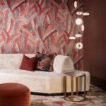 Moderne woonkamer met Arte Chintz-behang uit de Essentials Les Tricots collectie, crèmekleurige bank, ronde bijzettafel en design hanglamp.