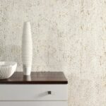 Moderne witte kast met houten blad, versierd met een geribbelde vaas en schaal, tegen een Arte Cobra-CA02 muur met slangenhuidstructuur.