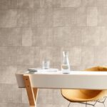 Moderne interieursetting met Arte Cuadro behang uit de Gitane collectie in zandkleur, een houten bureau en een designstoel.