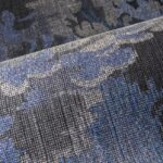 Detail van het Arte Diore 48011 behang uit de Les Forêts collectie met een geweven textuur in grijs-, blauw- en zwarttinten.