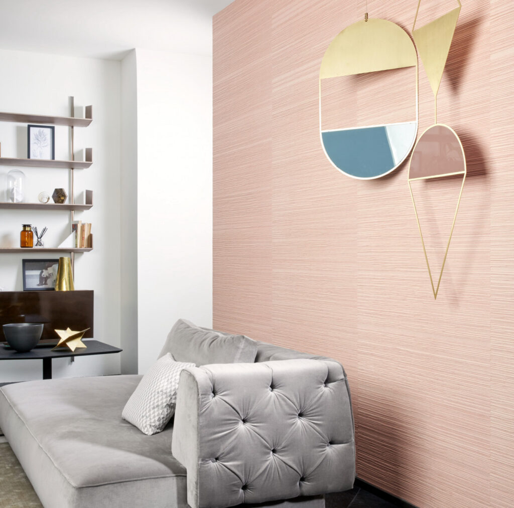 Moderne woonkamer met roze Arte Drift behang, een grijze fluwelen chaise longue en een gouden wanddecoratie.