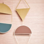 Detail van een woonkamer met Arte Drift behang in roze tint en decoratieve geometrische wandplanken.