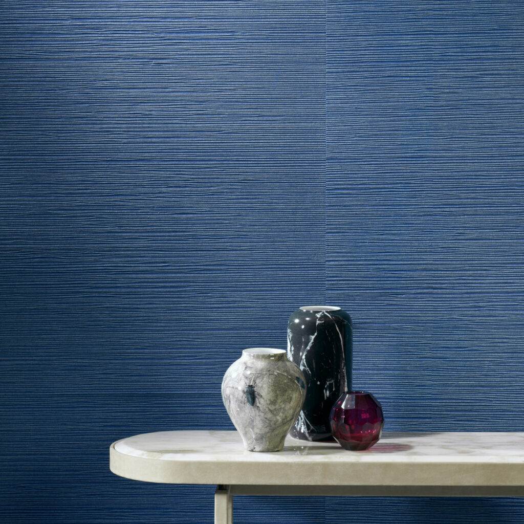 Marmeren tafel met drie decoratieve vazen tegen blauw Arte Drift behang in een moderne woonkamer.