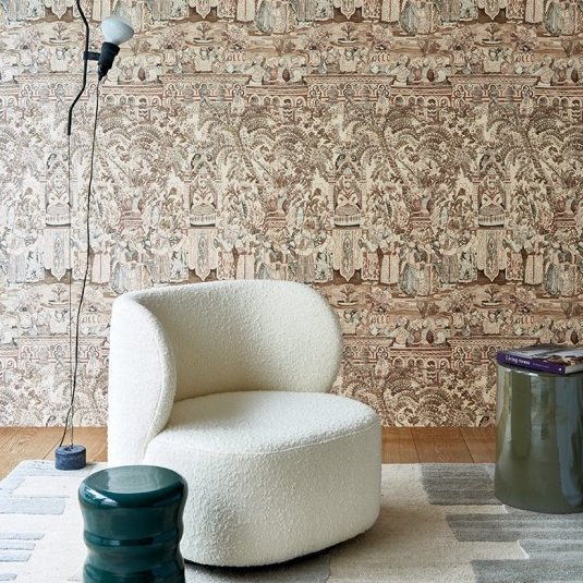 Sfeervolle zithoek met een crèmekleurige designstoel en decoratief Arte Emperador behang uit de Gitane collectie.