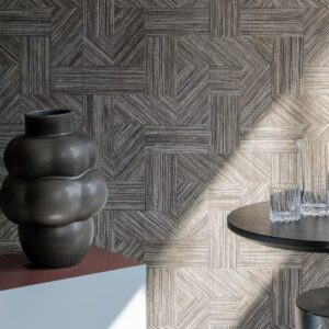 Moderne interieursetting met Arte Essentials Tangram Intarsio 24047 wandbekleding, een organisch gevormde vaas en glazen op een ronde tafel.