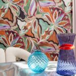 Kleurrijk interieur met Arte Essentials Tangram Myriad-24100 behang en decoratieve blauwe vazen op een glazen tafel.