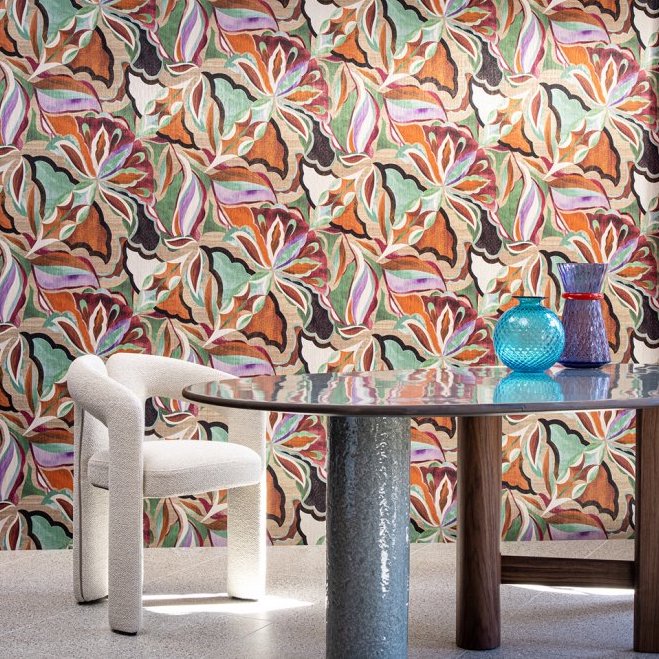 Interieur met kleurrijk Arte Essentials Tangram Myriad 24100 behang, een ronde tafel en een witte designstoel.