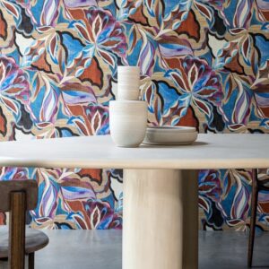 Ronde tafel met keramische vazen en borden voor een kleurrijk Arte Tangram Myriad-24102 bloemenbehang.