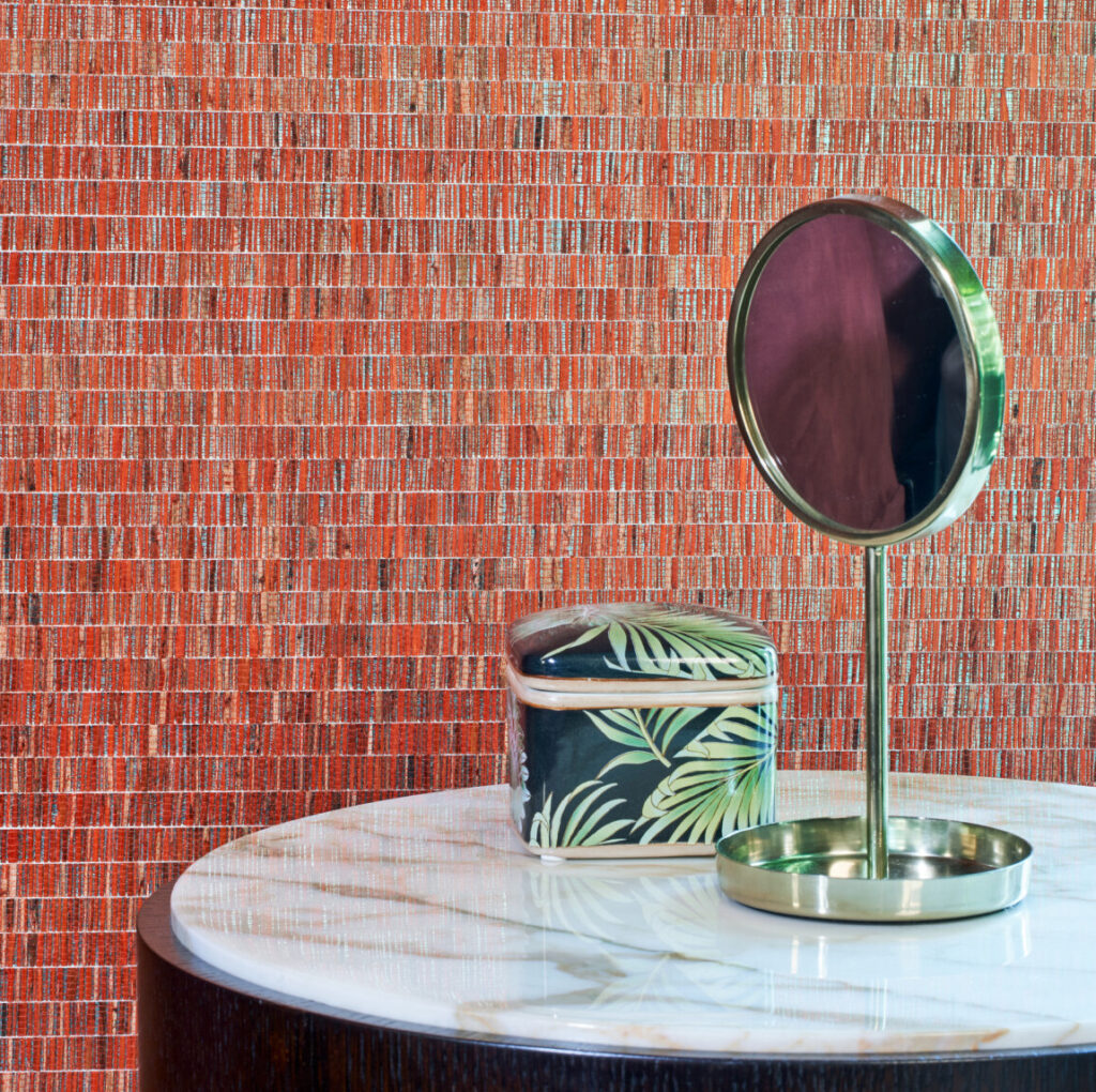 Close-up van een slaapkamer met rood Arte Fringe behang, een marmeren tafel, een ronde spiegel en een sieradendoosje met bladmotief.