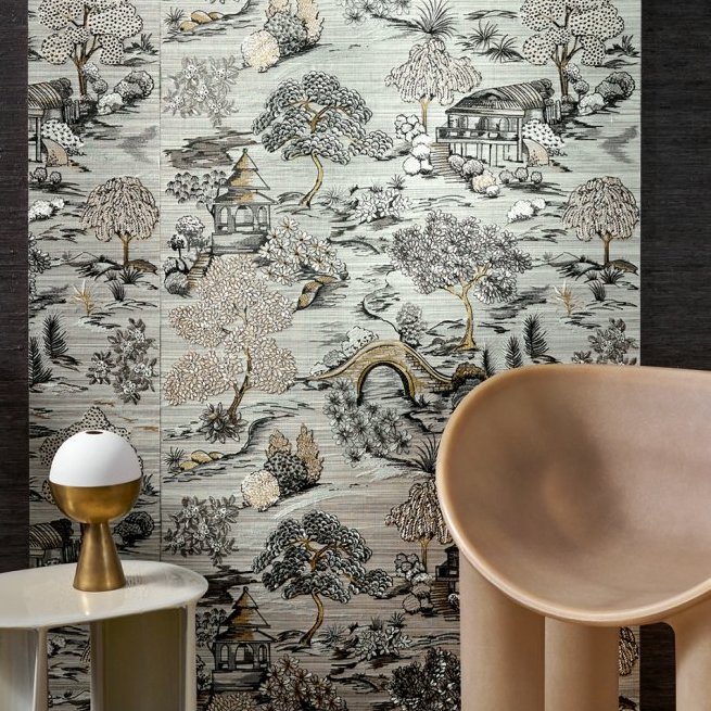 Decoratief behang met een Aziatisch geïnspireerd landschapspatroon uit de Arte Gardens of Okayama collectie, achter een moderne stoel en bijzettafel.