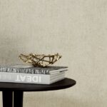 Stijlvolle interieursetting met Arte Granville behang, een moderne schaal en designboeken op een ronde tafel.