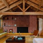 Sfeervol interieur met een houten plafond, een open haard met Arte Icarus Indomito wandbekleding en retro-meubels.