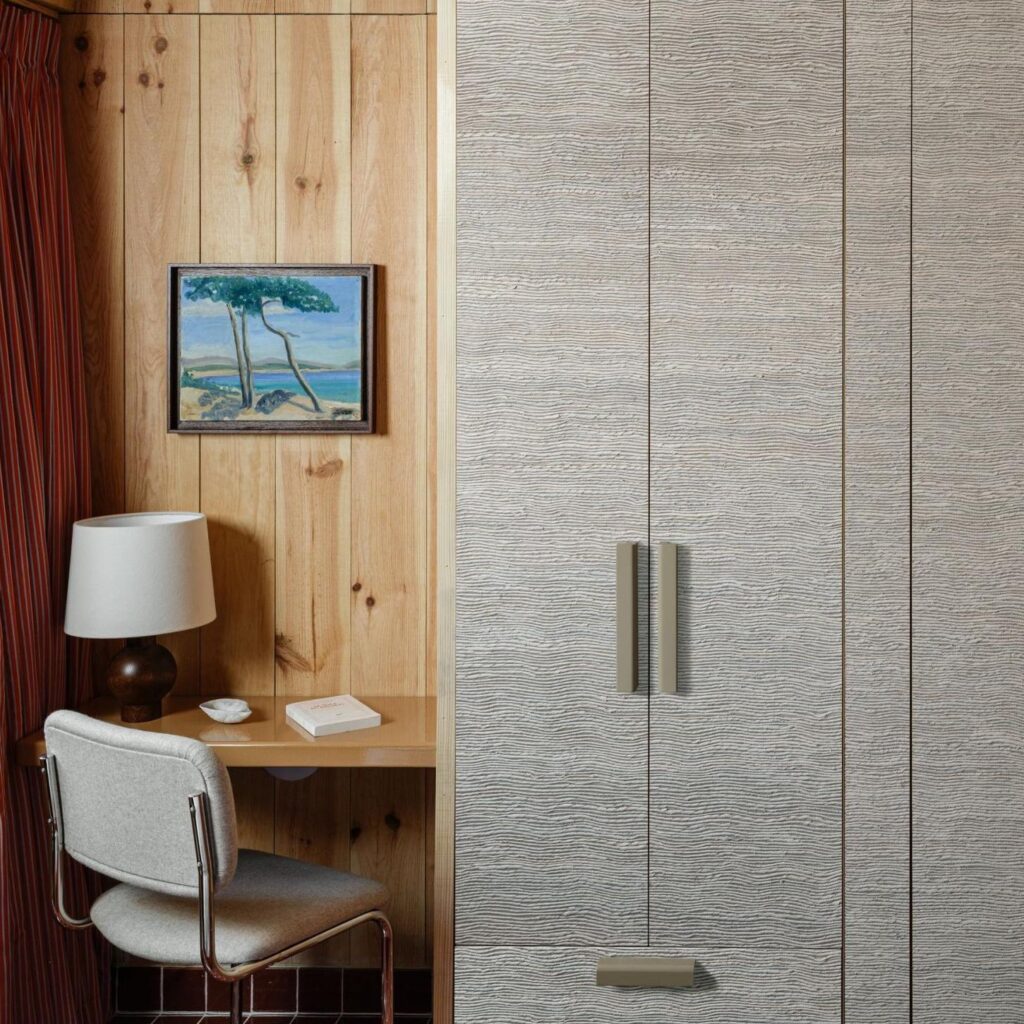 Kleine werkplek met houten wandbekleding, het Arte Icarus Penumbra 15740 behang en een schilderij boven het bureau.