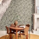 Eettafel met rotan stoelen voor een muur met Arte International Éclat 48042 Smoke Les Forêts behang in een natuurlijke setting.