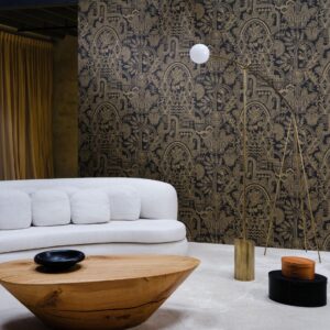 Modern interieur met een lichtgrijze bank en houten tafel tegen een decoratieve zwarte muur met goud patroon van Arte Joie 30811 behang.