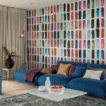 Moderne woonkamer met een kleurrijk Arte Joy Zest JOY71 behang en een groot blauw loungebankstel.