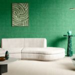 Modern interieur met een crèmekleurige bank en groen Arte KatanSilk 11504 behang op de muur.