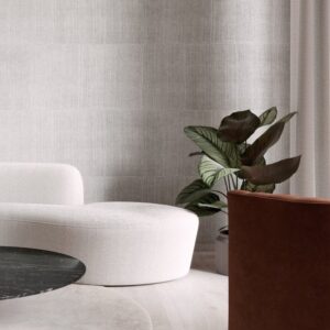 Moderne zithoek met Arte KatanSilk 11505 wit behang, een ronde witte sofa, een plant en een marmeren salontafel.