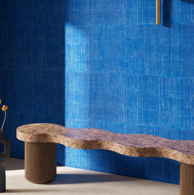 Golvend houten bankje voor een muur met blauw Arte KatanSilk 11506 behang in een moderne interieursetting.