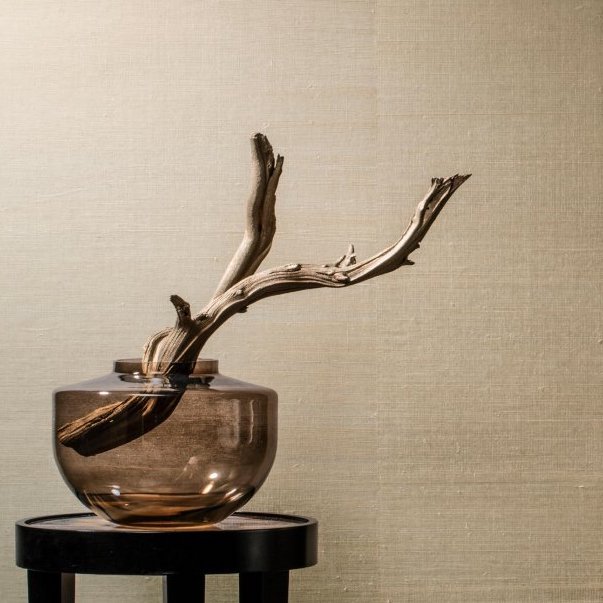 Glazen vaas met decoratief stuk hout staat voor beige Arte Line behang 80700B.