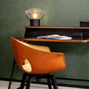 Designbureau met een leren Gioco-stoel van Arte en een tafellamp tegen een groene linnenstructuur wandbekleding.
