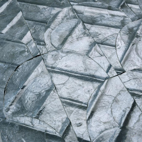 Detailopname van het Arte Luster Abalone 70323 wandbekledingsmateriaal met een glanzende, zilvergrijze textuur en geometrisch patroon.