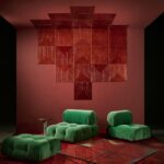 Groene loungefauteuils en een glazen salontafel in een modern interieur met rode Arte Luster Cornice 7033 wandbekleding.