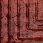 Detailopname van de glanzende rode textuur en reliëfstructuur van de Arte Luster Cornice 70333 Garnet wandbekleding.