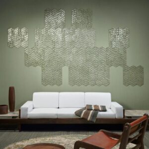 Een moderne woonkamer met een witte bank, decoratieve kussens en een wand bekleed met Arte Luster Lucea 70312 wandpanelen in een geometrisch patroon.