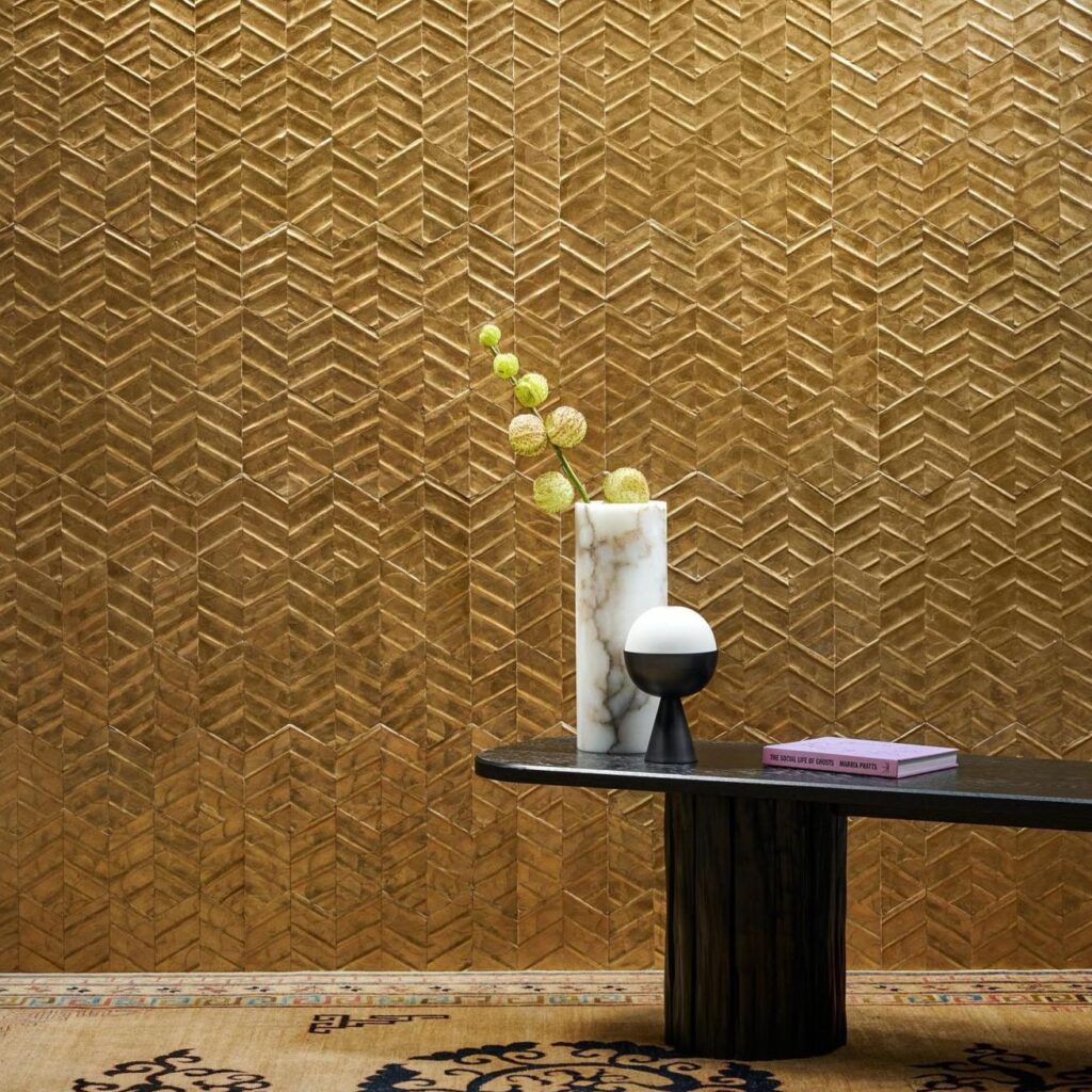 Sfeervolle interieursetting met Arte Luster Lucea 70313 goudkleurig behang, lage zwarte tafel, marmeren vaas, tafellamp en boek.