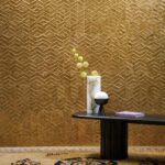 Sfeervolle interieursetting met Arte Luster Lucea 70313 goudkleurig behang, lage zwarte tafel, marmeren vaas, tafellamp en boek.