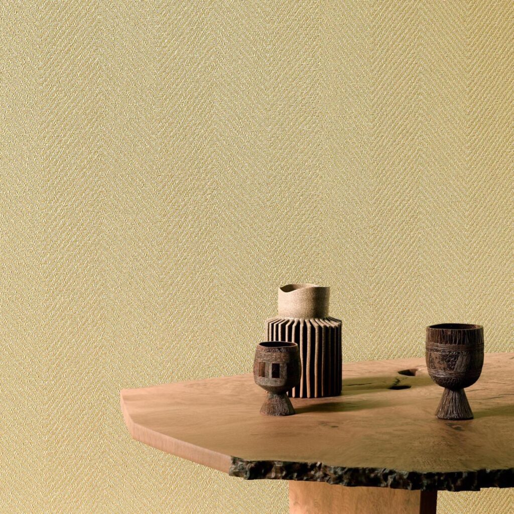 Houten tafel met decoratieve objecten voor een beige wand met subtiel visgraatpatroon uit de Arte Marquesa Atuona 31723 collectie.