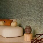 Zithoek met beige chaise longue, ronde kussens en aardewerken vaas voor een wand met Arte Marquesa Cyperus behang.
