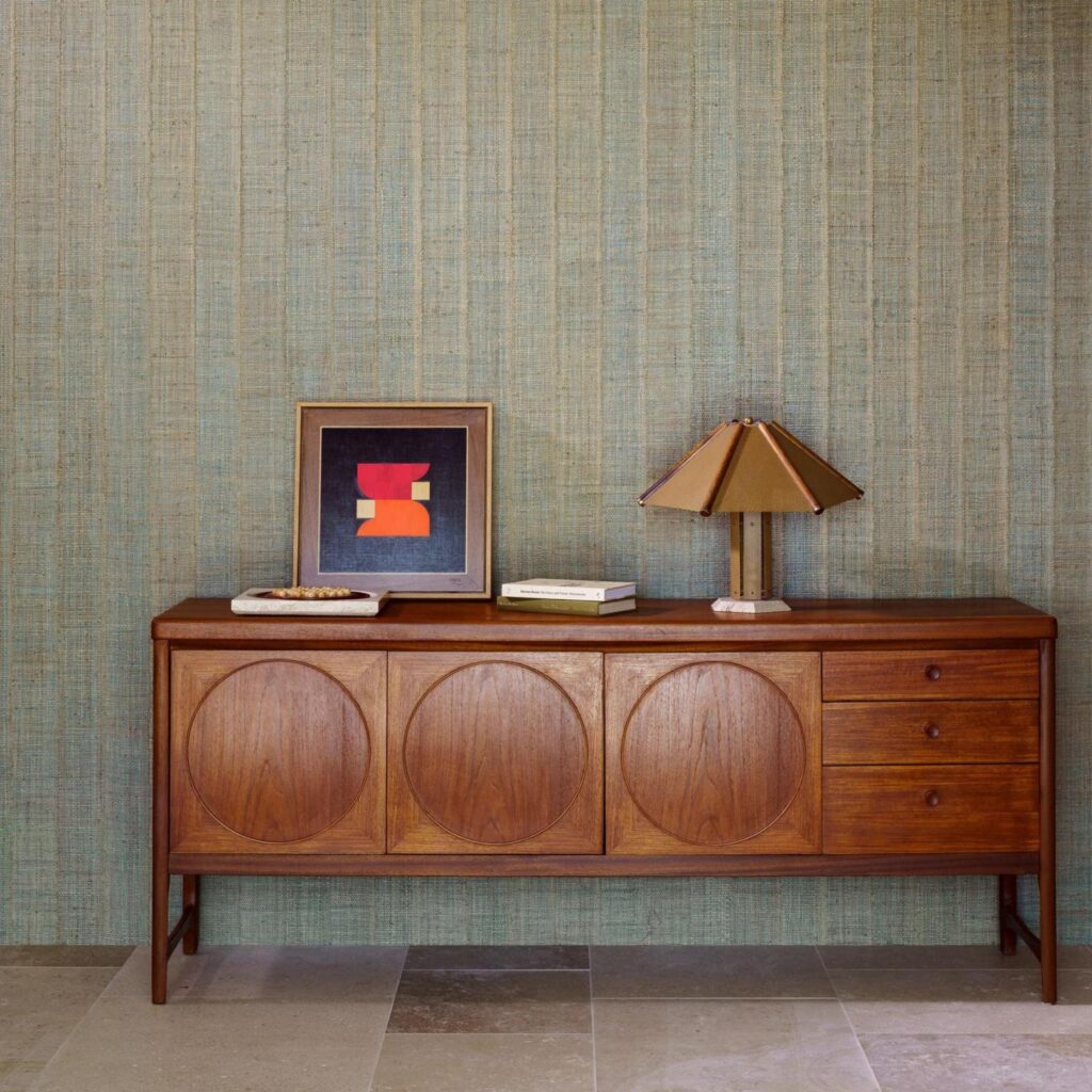 Mid-century dressoir tegen een muur met Arte Melaky Farini 40724-behang in een rustieke, geweven textuur.