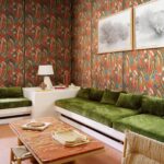 Woonkamer met kleurrijk Arte Melaky Mandrava behang, groene fluwelen banken en een rood marmeren salontafel.