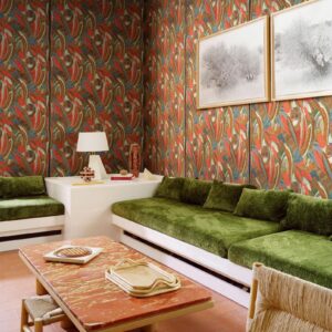 Woonkamer met kleurrijk Arte Melaky Mandrava behang, groene fluwelen banken en een rood marmeren salontafel.