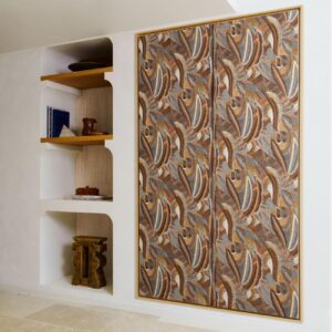 In een modern interieur hangt het wandpaneel Arte Melaky Mandrava 40761 met een organisch bruin en okergeel patroon naast een ingebouwde witte wandkast met houten planken.