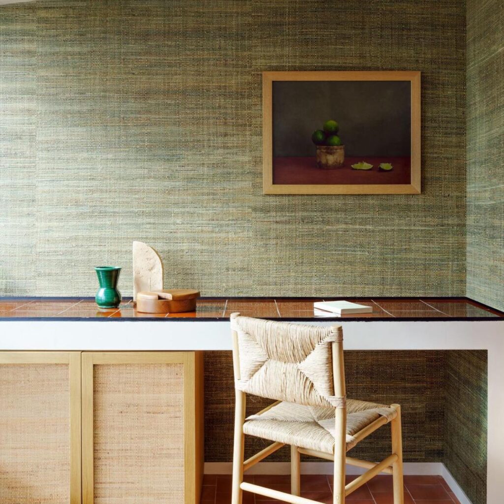 Sfeervol interieur met Arte Melaky Tana behang, een houten bureaustoel en kunstwerk met citrusvruchten aan de muur.