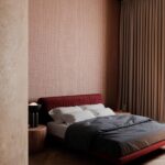 Sfeervol ingerichte slaapkamer met een rode Arte Merino Lana 63510 wandbekleding achter een modern bed.